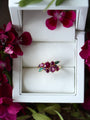 Ring with gemstones in a white box surrounded by pink flowers