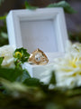 Gold ring with a diamond on a white box surrounded by flowers