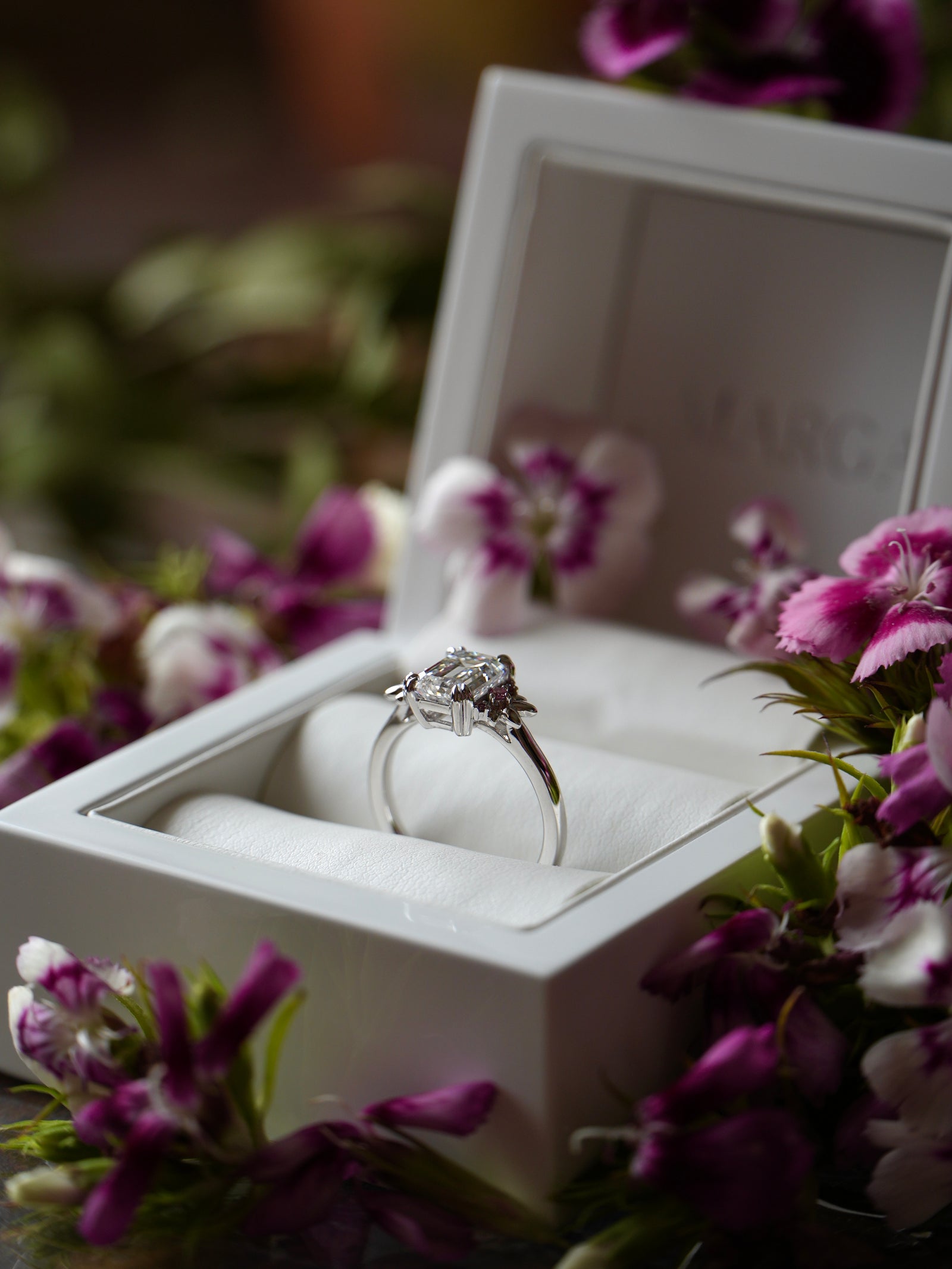 Diamond ring in a white box with flowers around