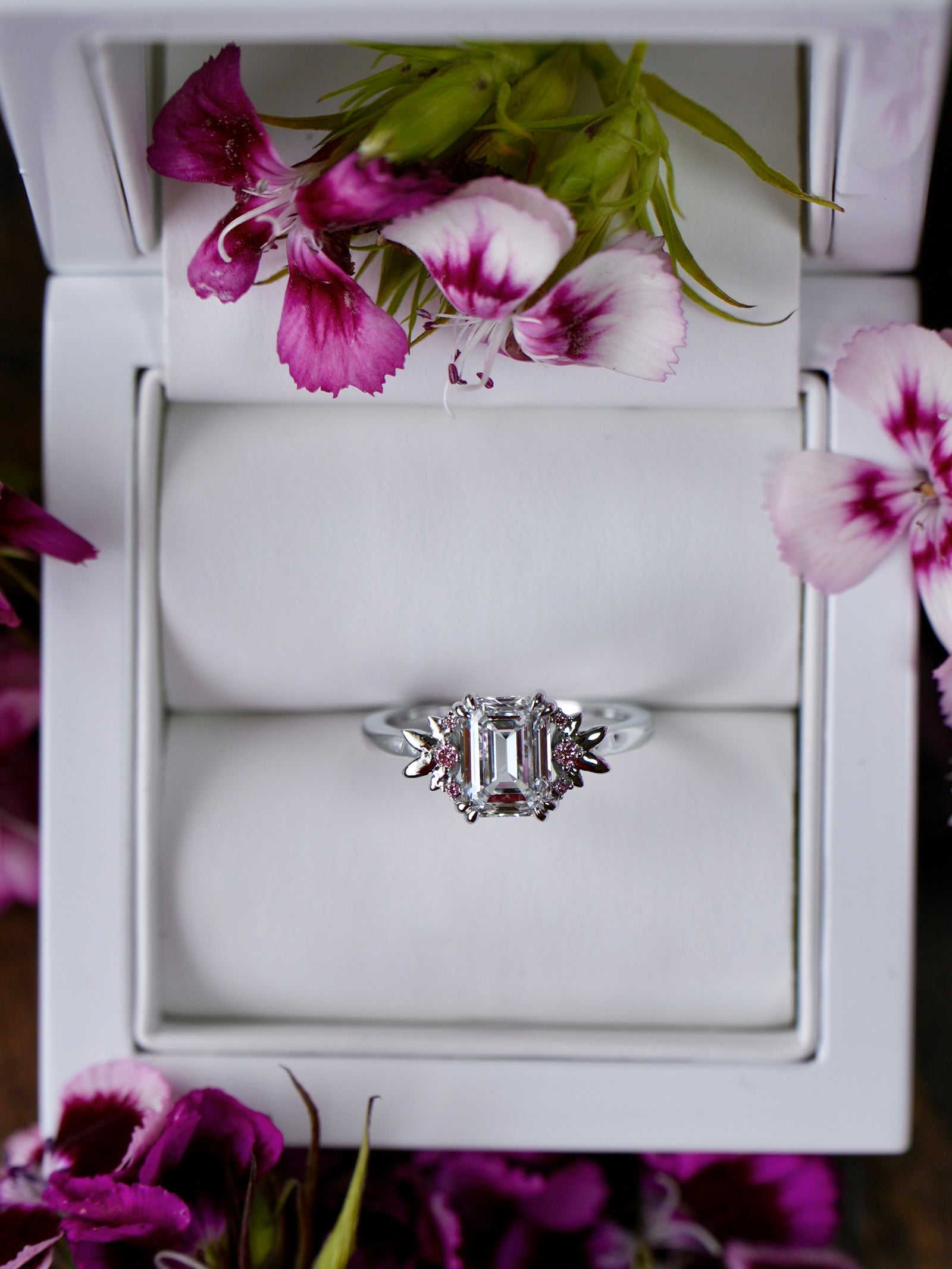 Silver ring in a white jewelry box with pink flowers around