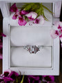 Silver ring in a white jewelry box with pink flowers around