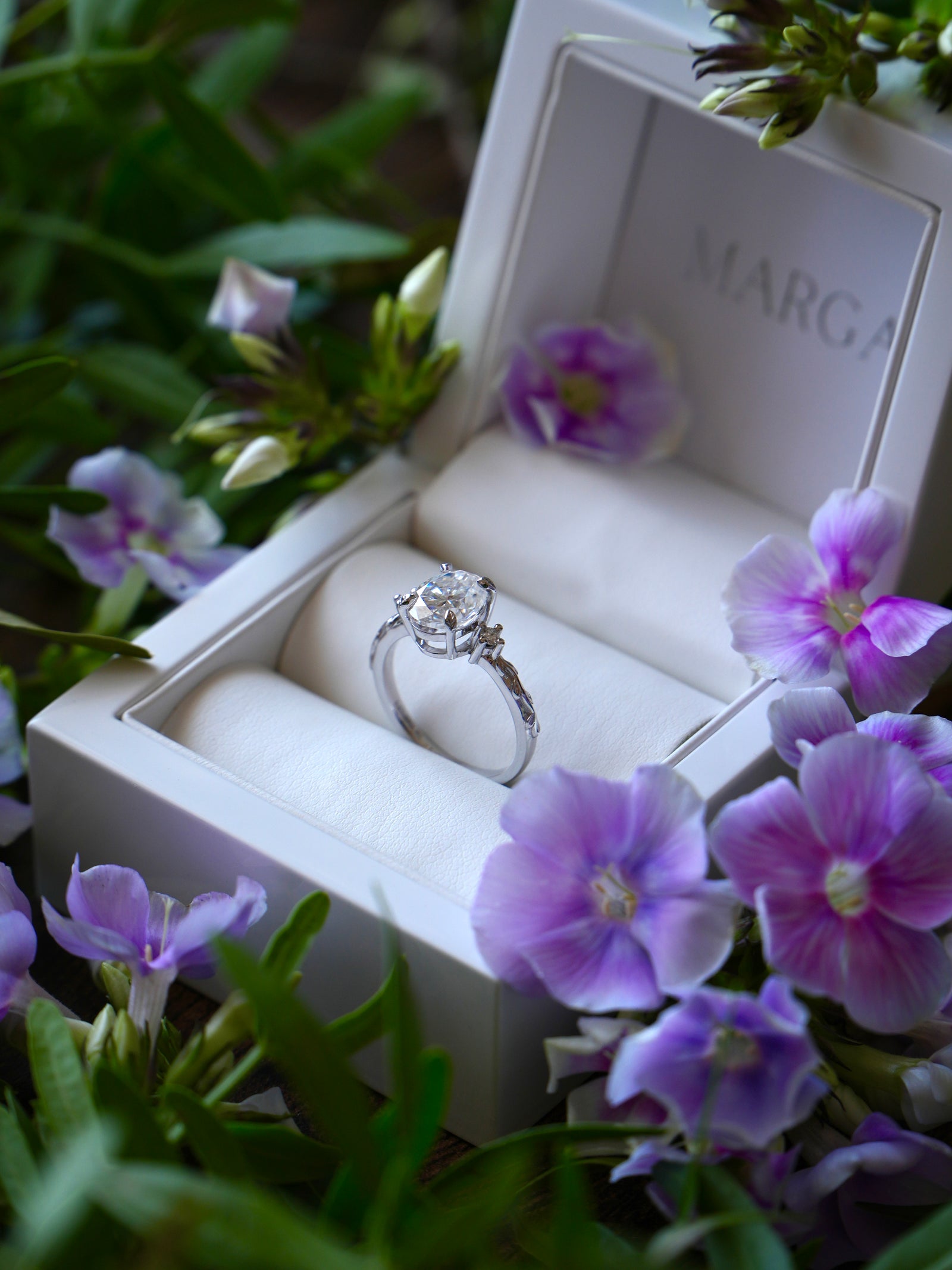 Diamond ring in a white box with purple flowers around