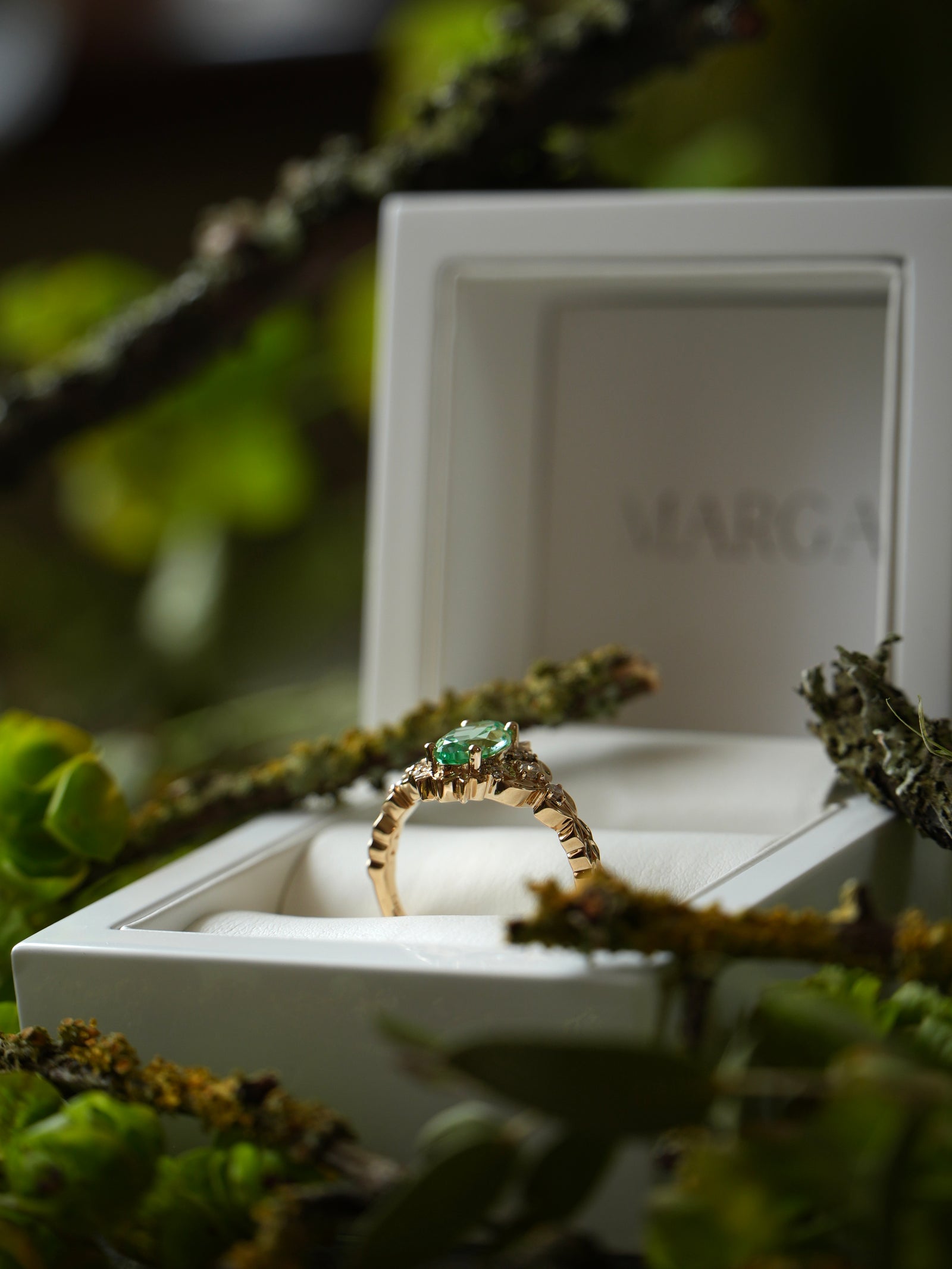 Gold ring with a green gemstone in a white jewelry box on a natural background