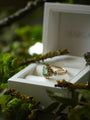 Gold ring with a green gemstone in a white box on a natural background