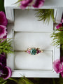 Ring with gemstones in a jewelry box surrounded by flowers and greenery
