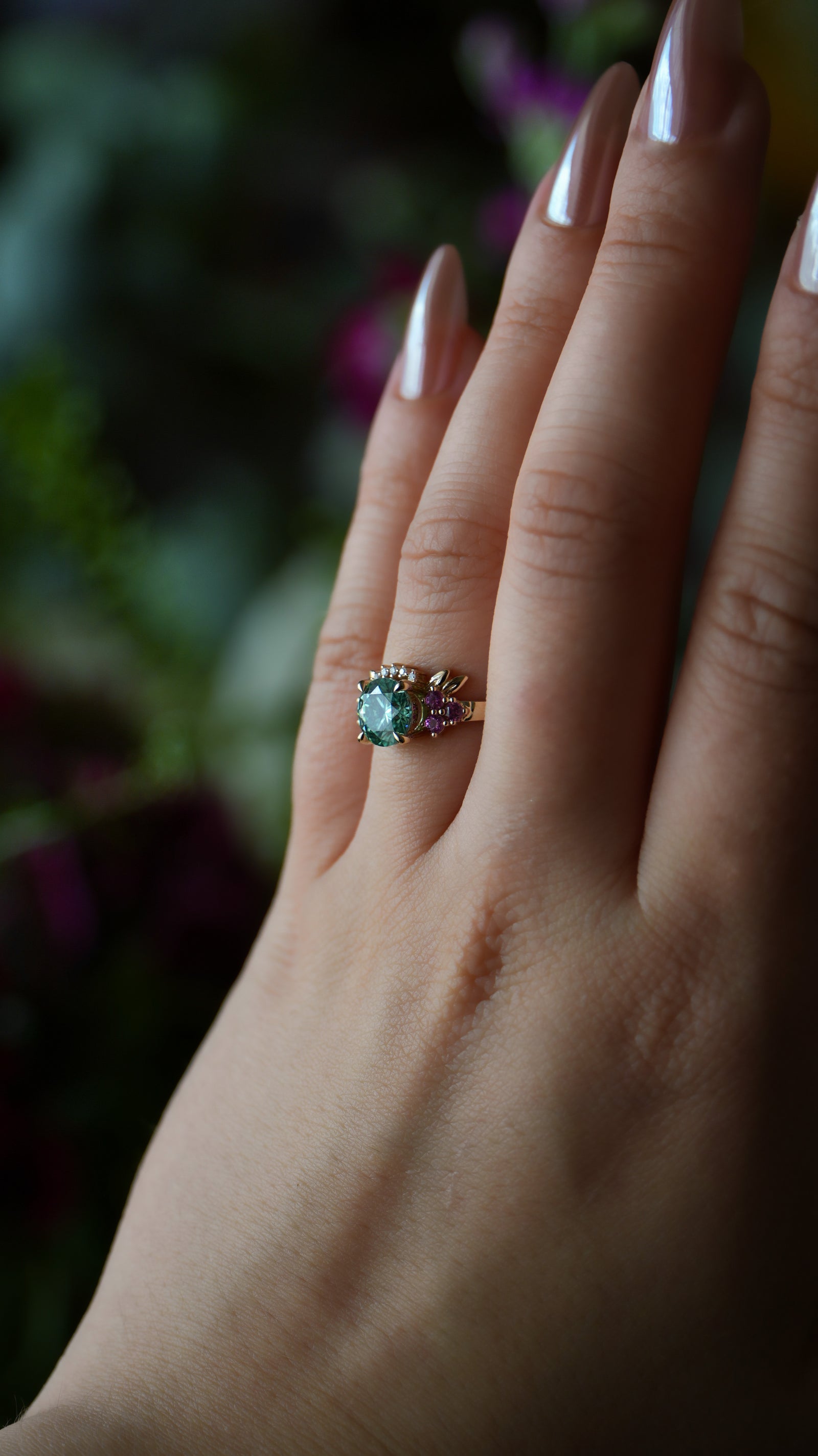 Hand wearing a ring with a green gemstone against a blurred background