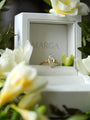 Gold ring with a diamond in a 'MARGA' box surrounded by white flowers