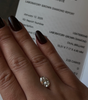 Hand wearing a diamond ring with an International Gemological Institute report in the background