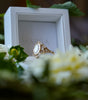 Gold ring with a large gemstone in a white box surrounded by flowers