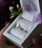 Diamond ring in a white box with purple flowers