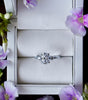 Diamond ring in a box with purple flowers around