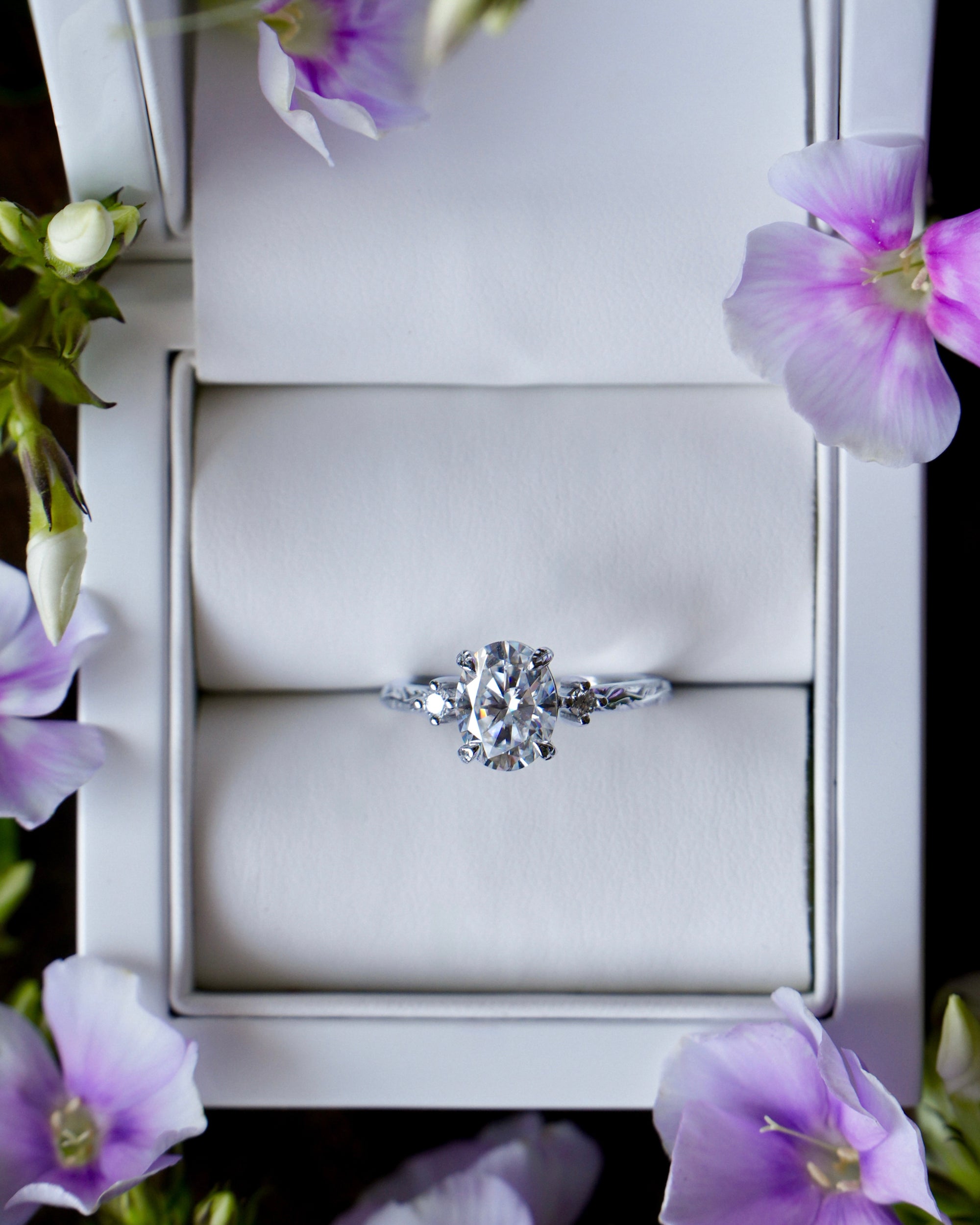 Diamond ring in a box with purple flowers around