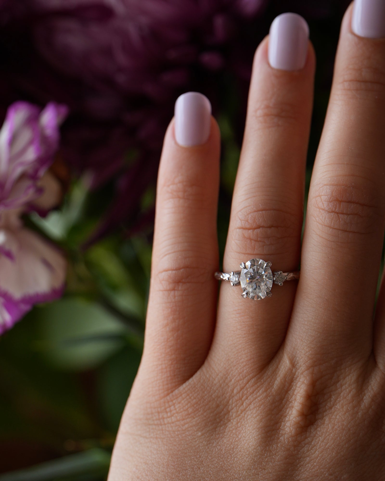 Diamond ring on a hand with a blurred floral background