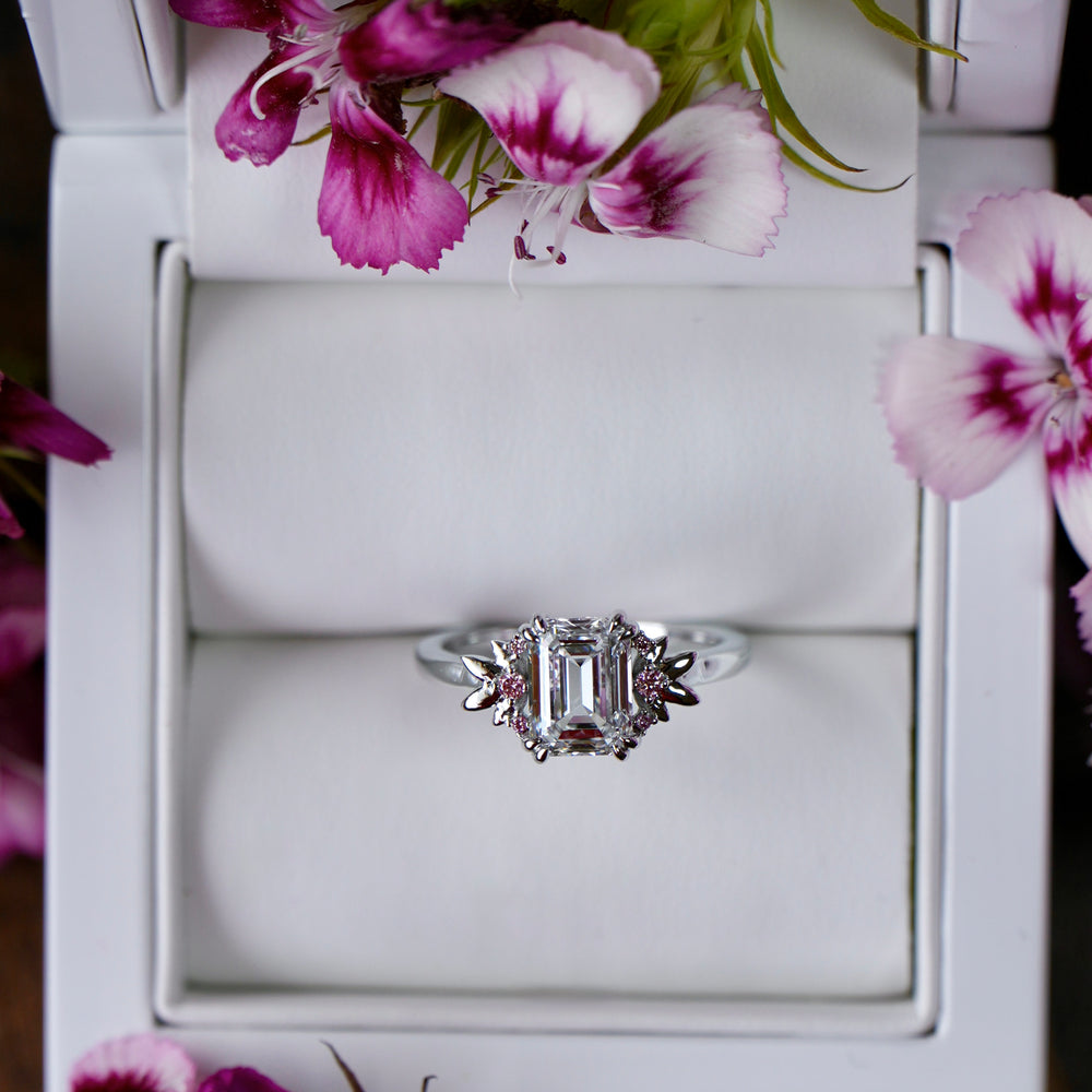 Silver ring in a white jewelry box with pink flowers around