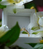 Gold ring on a white box with white flowers in the background