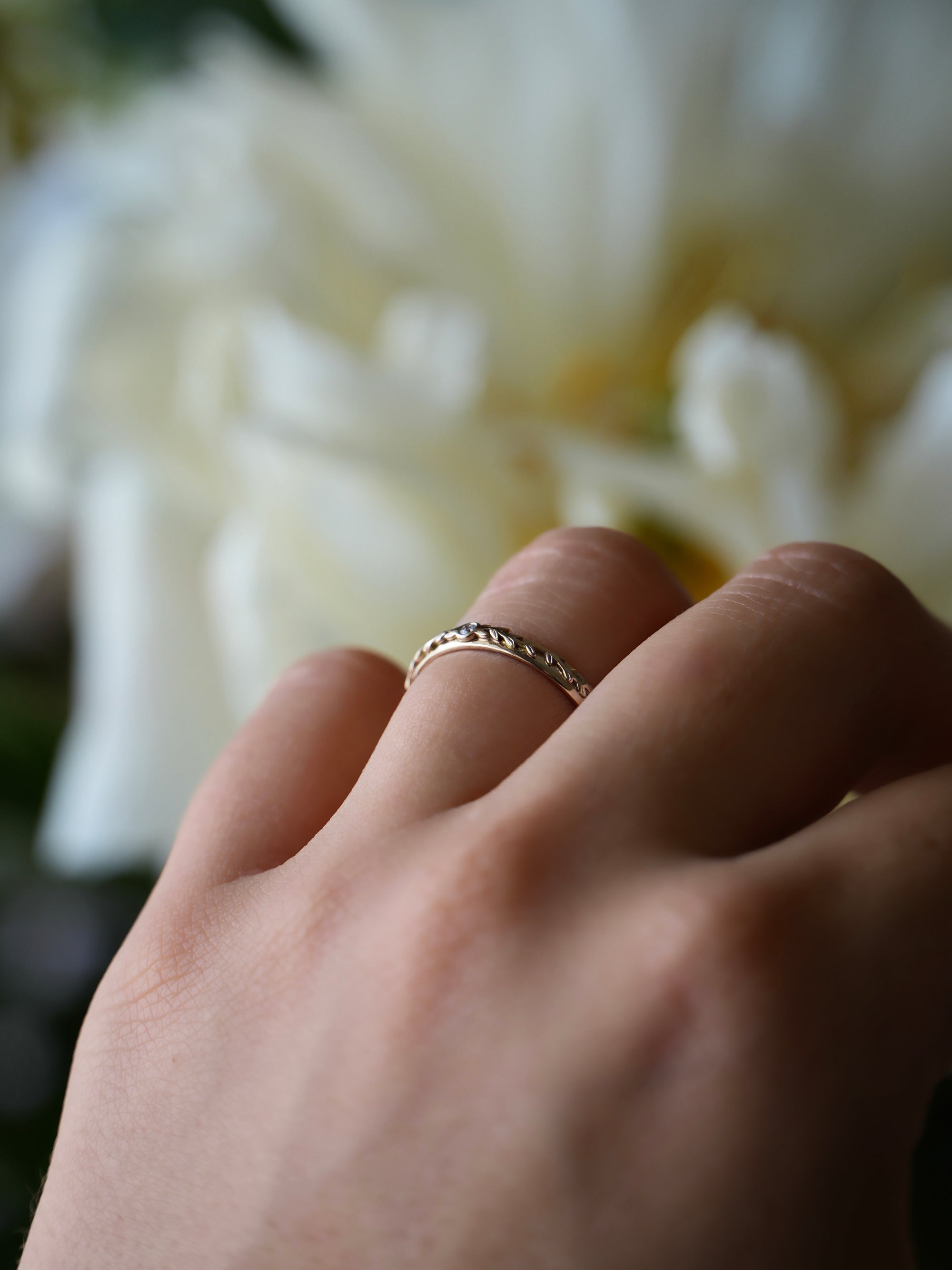Gold ring on a hand with a blurred floral background