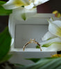 Gold ring on a white box with white flowers in the background