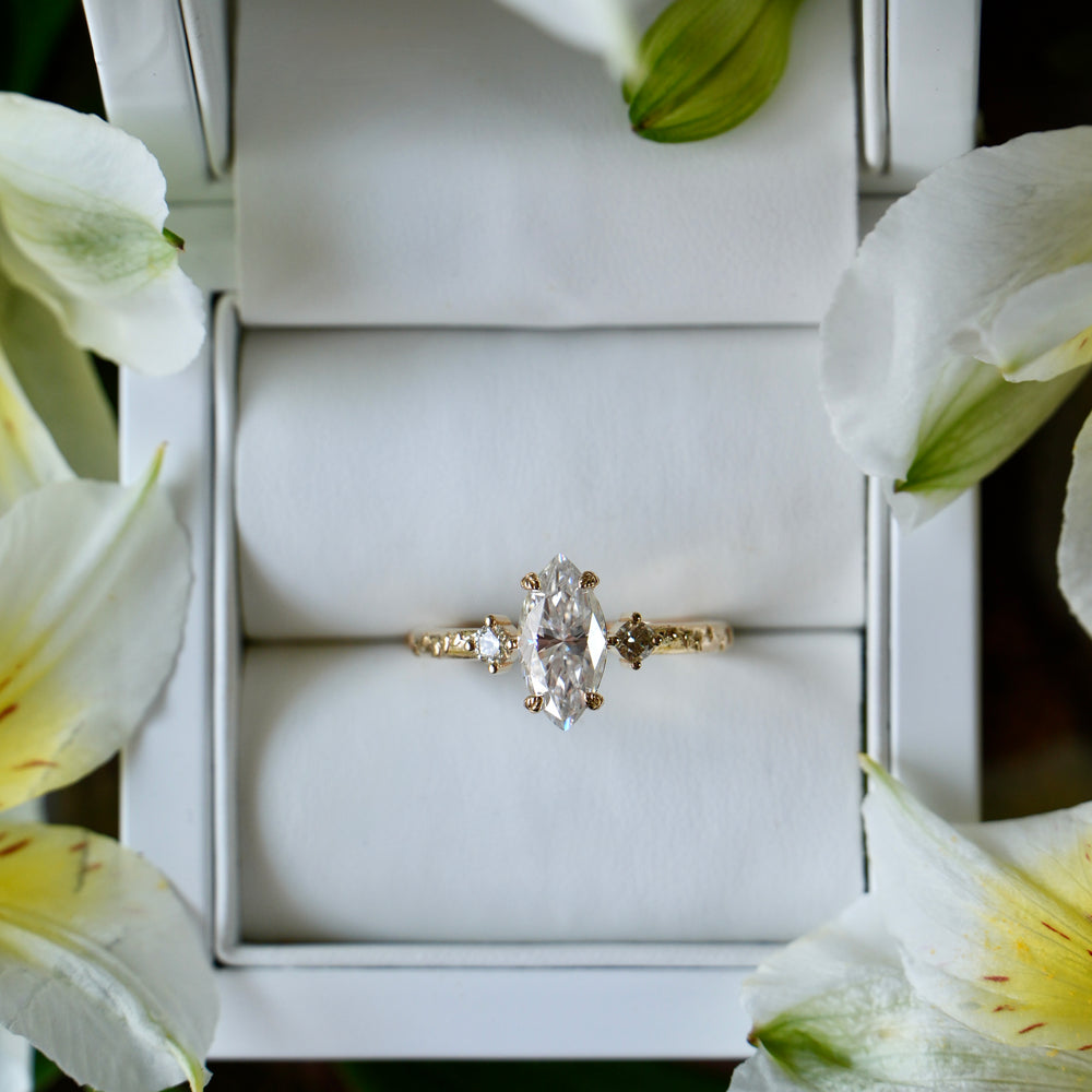 Diamond ring in a white box surrounded by white flowers