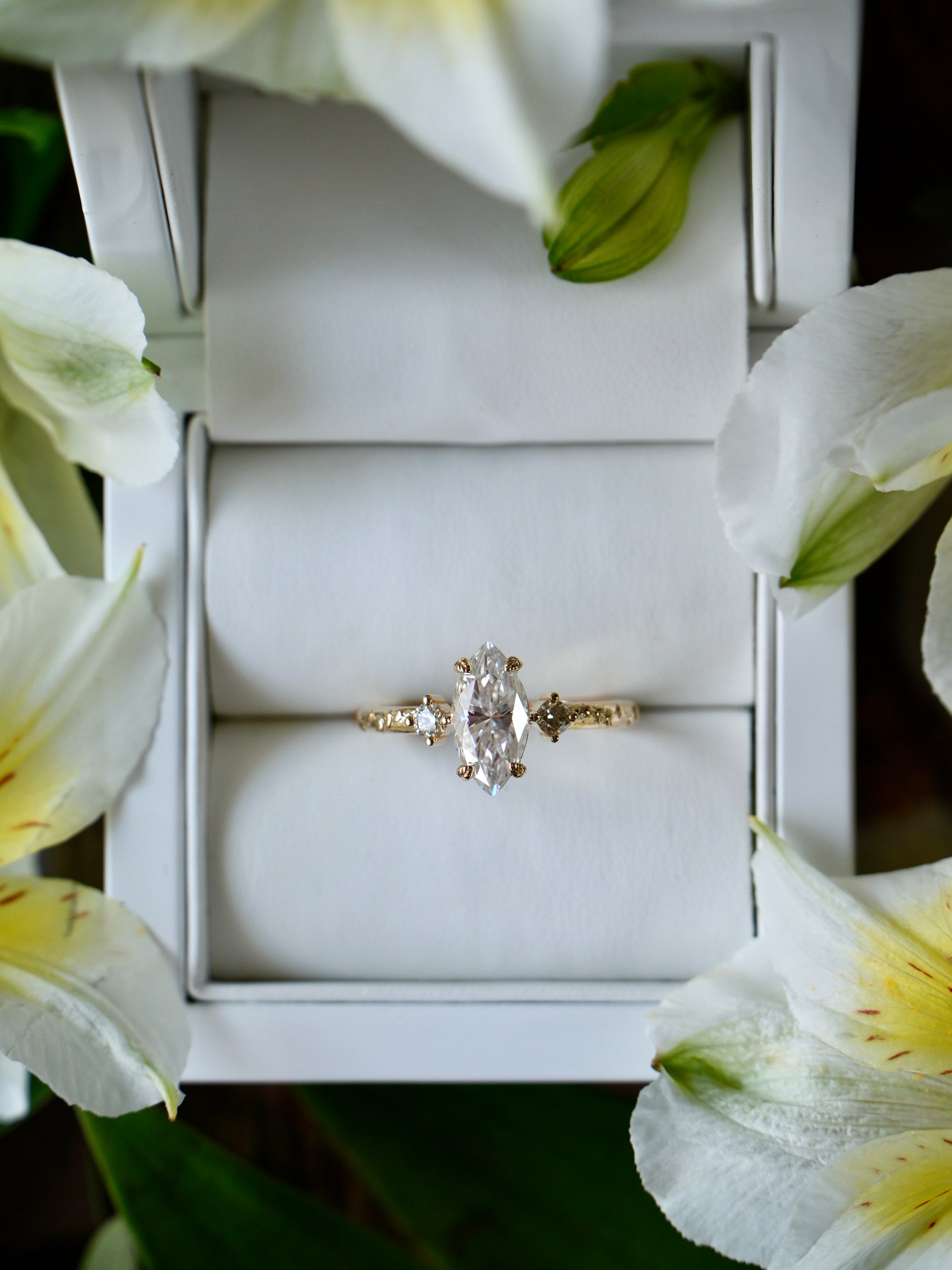 Diamond ring in a white box surrounded by white flowers