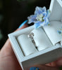 Silver ring in a white jewelry box with floral decorations.