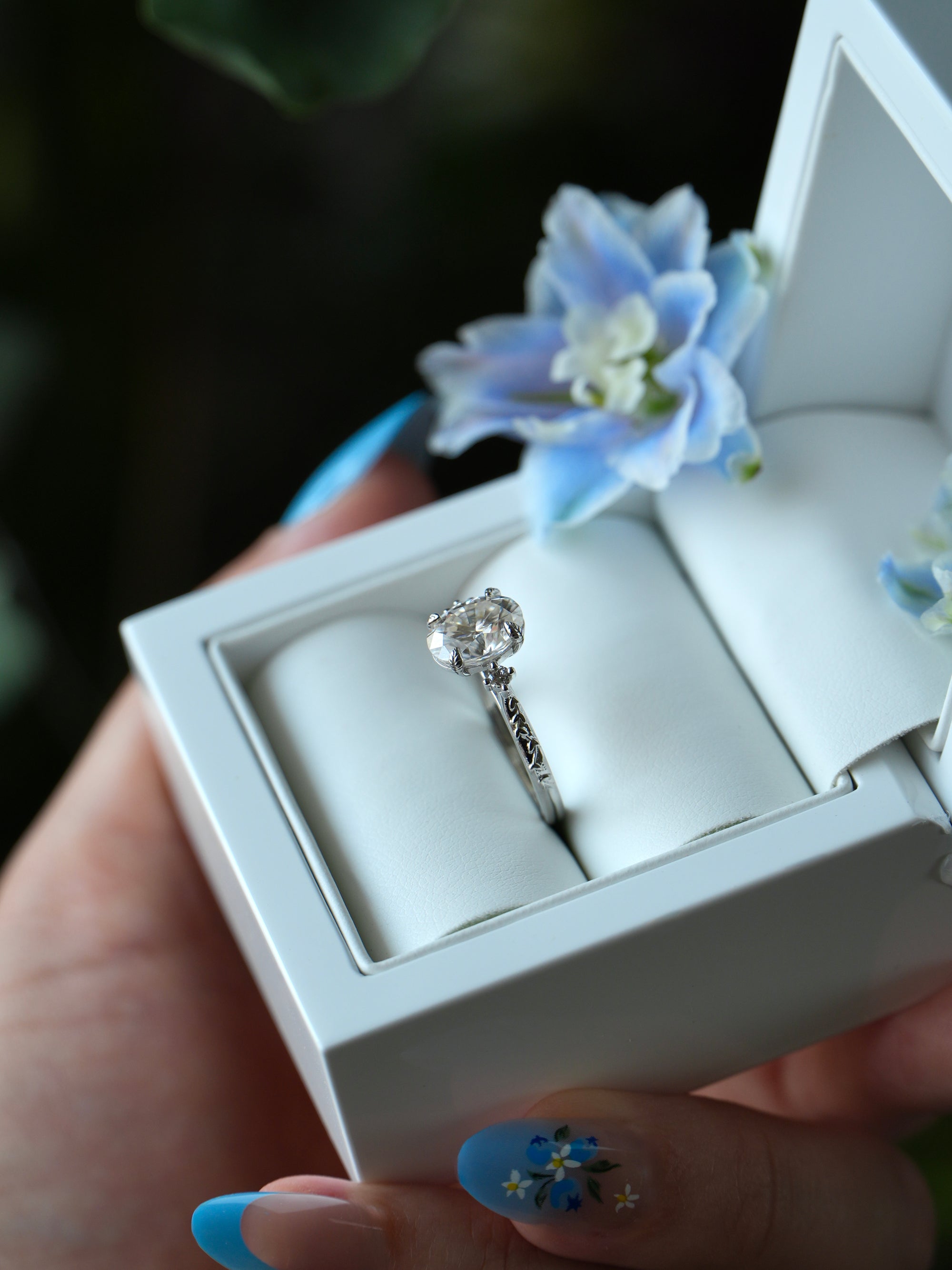 Silver ring in a white jewelry box with floral decorations.